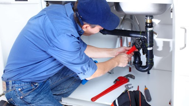 Mature plumber fixing a sink at kitchen